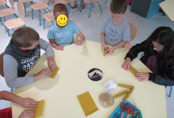 Enfants confectionnant des bougies à la cire d'abeille